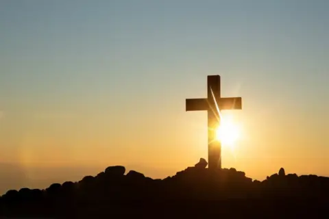 a-cross-in-a-hill-with-a-sunset-background